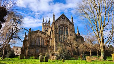 Exterior of a church with a graveyard with blue skies 