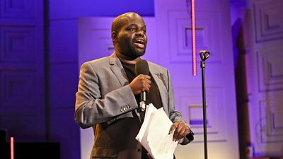 Photo of Daliso Chaponda speaking into a microphone on stage from The Arts Hour on Tour