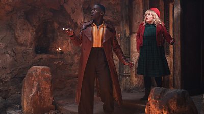 The Doctor and Joy look shocked as they enter a large stone room