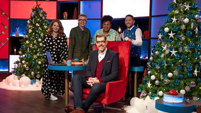 Contestants Jennie McAlpine, Gareth Malone, Desiree Burch and Jon Richardson stand around Richard Osman, who sits in his bright red chair in a festively decorated studio