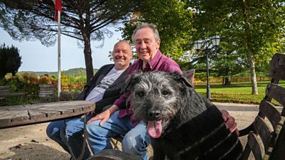 Bob Mortimer and Paul Whitehouse sit on a bench with Ted the dog