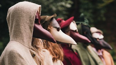 Line of people wearing Plague doctor masks 