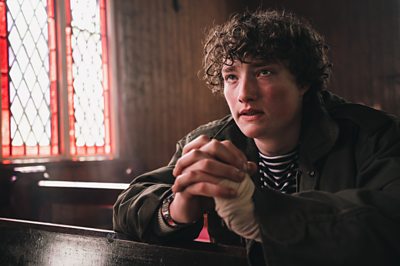 Con (Cal O'Driscoll) praying and looking sad/concerned at a Church pew