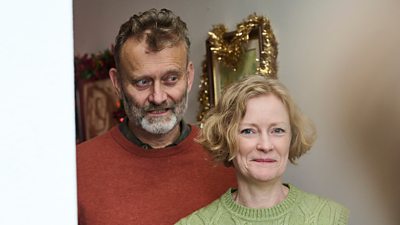 Pete (Hugh Dennis) and Sue (Claire Skinner) stand in a doorway smiling