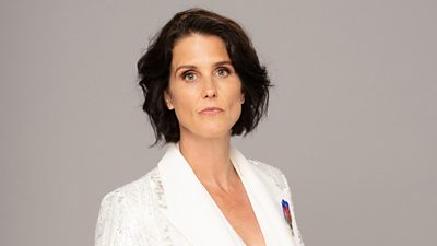 Eve (Heather Peace) wears a white suit and looks directly to camera