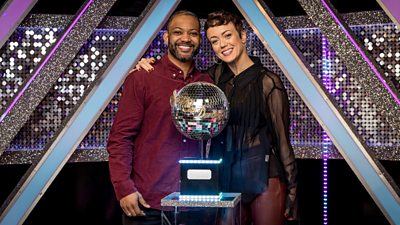 JB and Lauren stand together behind the Strictly Come Dancing glitterball trophy in the It Takes Two studio