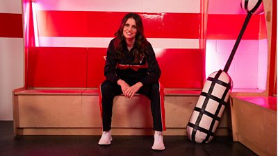 Ellie Taylor sits on a wooden bench in the Gladiators changing room, smiling for the camera