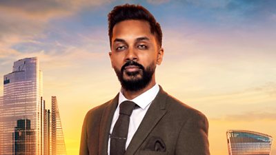 Dr Jana wears a dark woollen blazer with a dark brown tie with tie clip and pocket square. He has a bushy beard and moustache. A backdrop of the London skyline at sunset 