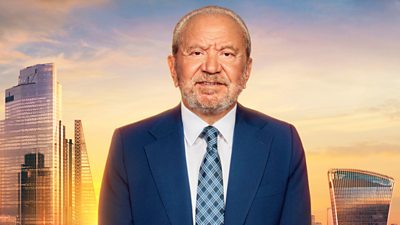 Lord Sugar wears a navy suit and chequered blue tie. A sunset London skyline is in the background