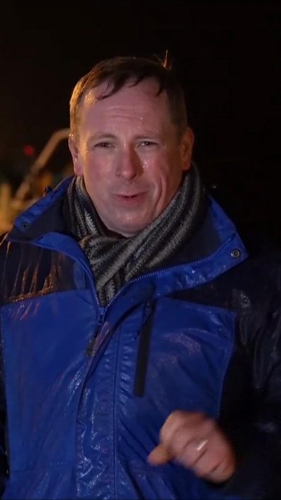 BBC Ireland correspondent Chris Page stands in a drenched blue raincoat on the western coast of Northern Ireland