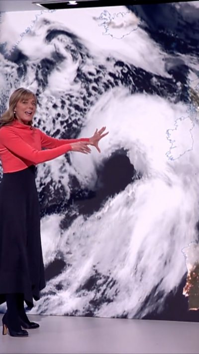 Louise Lear stood in front of clouds swirling satellite image over UK