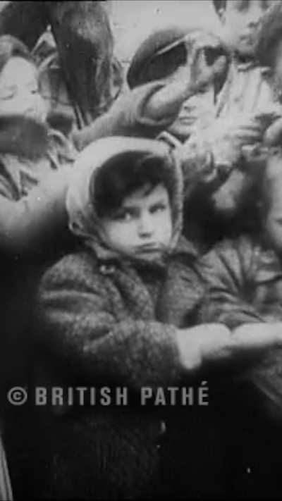 A child prisoner rolls up sleeve to show camera their camp number