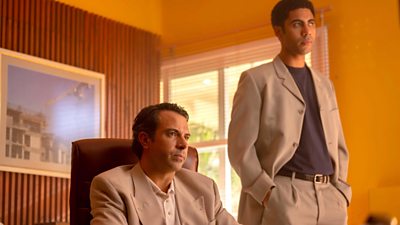 Tom Cullen and Joshua Samuels in an office that is very orange