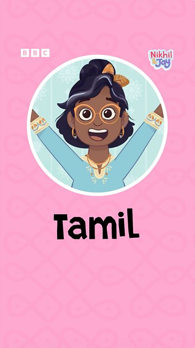 A south Indian woman wearing glasses smiles, cheerily raising her hands in celebration.