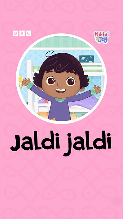 A young south Indian boy with a curl on his head smiling, waving his arms in enthusiasm.