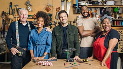 The cast of Clean It, Fix It stand in a workshop around a wooden bench