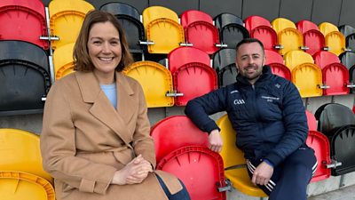 A female and a male sit on some plastic yellow and red stairs in a sports stadium