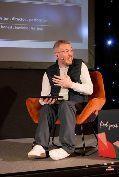 Speaker seated on stage