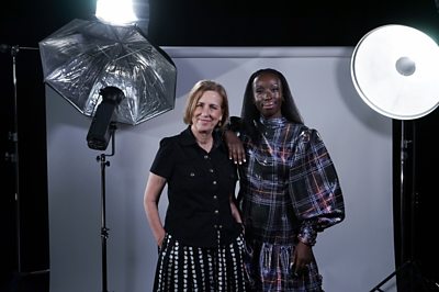 Kirsty Wark et Eunice Olumide se tenaient dans une configuration de photographie de style studio avec des lumières et des réflecteurs. Ils rient. Eunice porte une robe brillante tartan à manches surdimensionnée