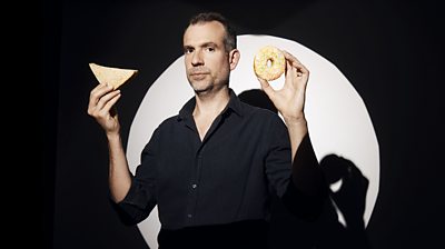 Chris van Tulleken holds a doughnut and a sandwich