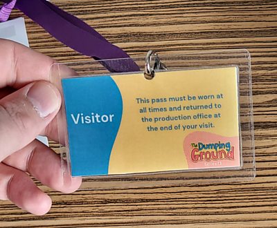 an image of a visitor pass and lanyard held in one hand for the Dumping Ground set
