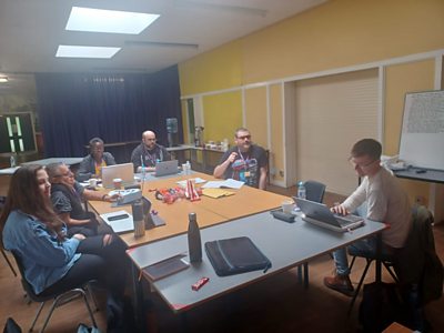 Six people sat around a table with laptops and notebooks at the Dumping Ground Story Conference