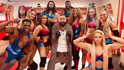 Chabuddy wearing a leopard shorts and robe stood in the Gladiators changing rooms surrounded by 10 Gladiators