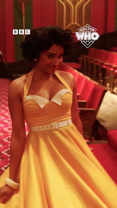 Belinda swishes her yellow 1950s style dress in a cinema.