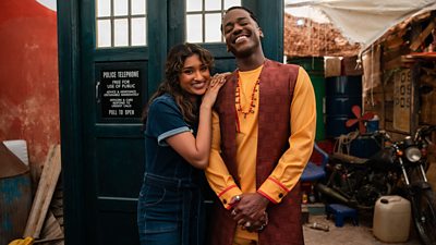 Ncuti Gatwa and Varada Sethu stand outside the TARDIS smiling