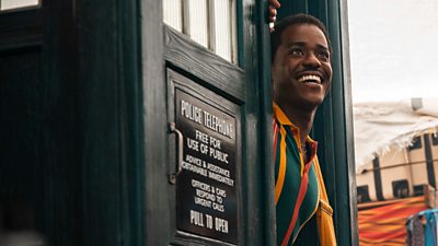 The Doctor smiles as he leans out the door of the Tardis