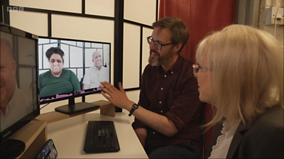 Two people looking at a TV screen where the smile tracker in use, analysing two people's faces.