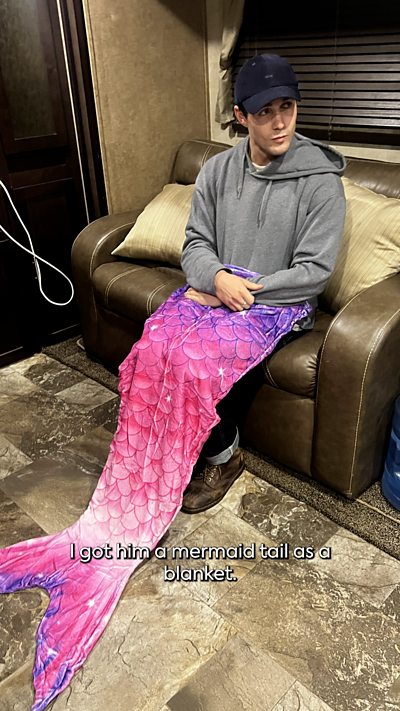Doctor Who's Conrad, a young man wearing a mermaid's tail behind the scenes.