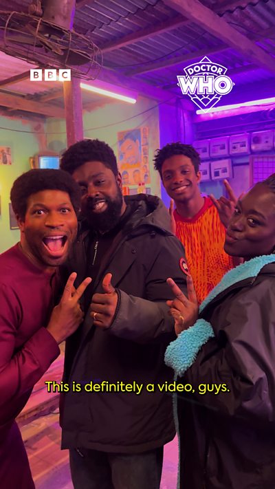 A group of people pose for the camera, text says "This is a video, guys!".