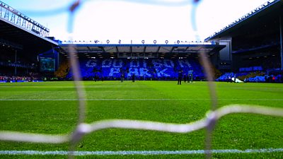 An image of Goodison Park pitch and stand taken through the goal net 