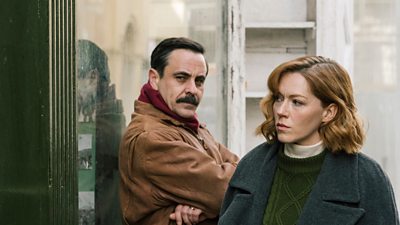 Emun Elliott and Charlotte Spencer in character on set of The Gold as DI Brightwell and DI Jennings, stood outside peering into a doorway