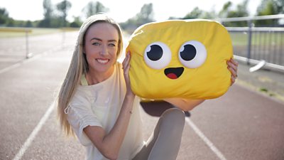 A woman sat down on a race track holding a yellow plushie with big eyes