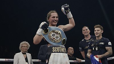 A female boxer in the ring with a medal