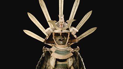 A statue dressed in a suit of armour including iron cuirass and an iron helmet trimmed with gilt copper with 7 swords fanning out the back of the helmet