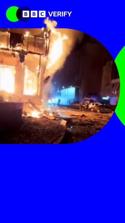 A composite image showing a building on fire in Donetsk in occupied Ukraine, alongside the BBC Verify logo.
