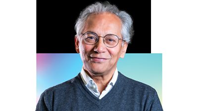 SSamir Shah, Chairman of the ѿý Group, wearing spectacles, a shirt and a grey jumper, stands and smiles, looking at the camera						