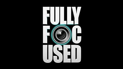 The text 'fully focused' on a black background with a camera lens in place of the 'o'