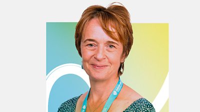 Rachel Thompson looks into the camera smiling, wearing a green dress and an Admiral Nurses lanyard