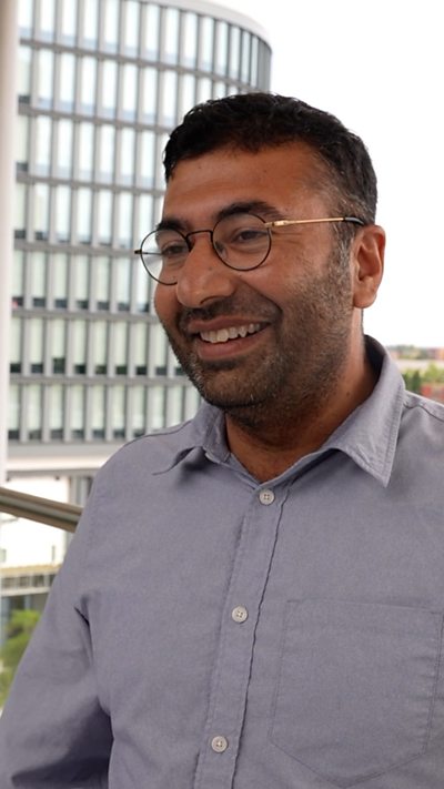 Hammad Hassan Rind, dyn yn gwenu ac yn gwisgo sbectol