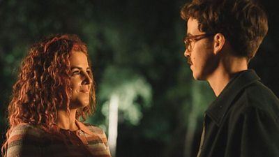 Jamie-Lee O'Donnell talking to Alex Lawther with a smile on her face. It is night-time and the characters are stood outside.