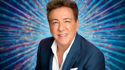 A head and shoulders shot of Ross King in a blue suit and white shirt, set against a glittering blue background