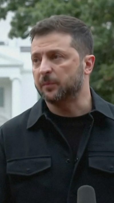 Zelensky in a black suit, stood before a microphone in front of the White House.