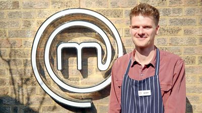 A portrait image of a contestant stood against an exposed brick wall, with the MasterChef logo behind him.