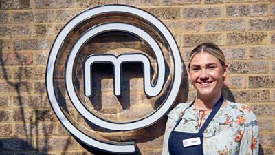 A portrait image of a contestant stood against an exposed brick wall, with the MasterChef logo behind her.