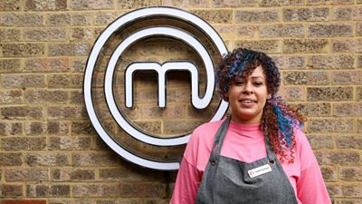 A portrait image of a contestant stood against an exposed brick wall, with the MasterChef circular white logo behind her.