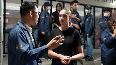 Zara having a conversation with a Thai police man. There are other police men and women also in shot.